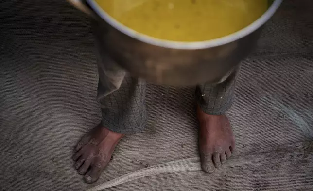 A Palestinian child carries a pot of soup received from a community kitchen in Khan Younis, Gaza Strip, on Saturday, May 3, 2025. (AP Photo/Abdel Kareem Hana)