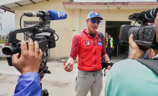 British mountain guide Kenton Cool, center, who scaled Mount Everest Sunday for the 19th time breaking his own record for the most ascents of the world’s highest mountain by a non-Sherpa guide speaks with journalists as he arrives at the airport in Kathmandu, Nepal, Tuesday, May 20, 2025. (AP Photo/Niranjan Shrestha)