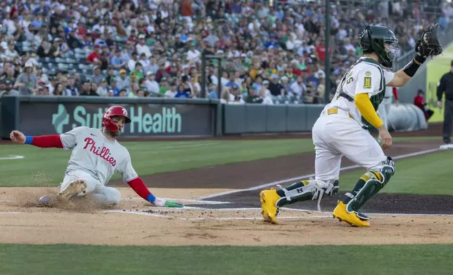Philadelphia Phillies' Bryce Harper, left, scores on a double hit by Nick Castellanos (not shown) during the first inning of a baseball game against the Athletics, Saturday, May 24, 2025, in West Sacramento, Calif. (AP Photo/Sara Nevis)