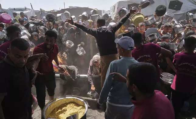 Palestinians struggle to get donated food at a community kitchen in Khan Younis, Gaza Strip, Friday, May 16, 2025. (AP Photo/Abdel Kareem Hana)