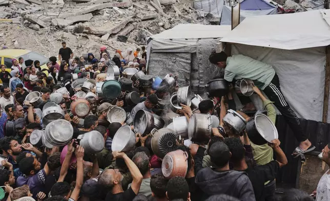 Palestinians struggle to get donated food at a community kitchen in Jabalia, northern Gaza Strip, Thursday, May 15, 2025. (AP Photo/Jehad Alshrafi)