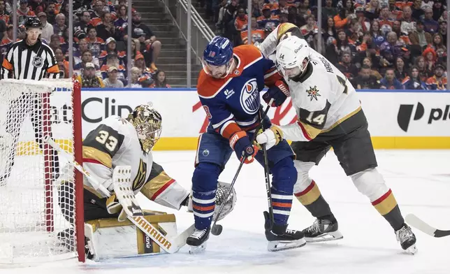 Vegas Golden Knights goalie Adin Hill (33) makes a save against Edmonton Oilers' Zach Hyman (18) as Golden Knights' Nicolas Hague (14) defends during the second period of Game 4 of a second-round NHL hockey playoff series in Edmonton, Alberta, Monday, May 12, 2025. (Jason Franson/The Canadian Press via AP)