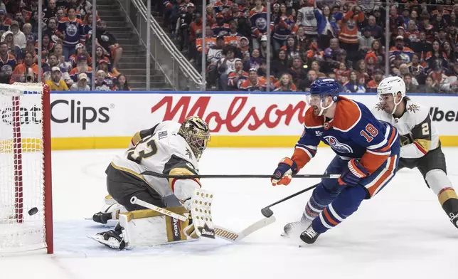 Vegas Golden Knights goalie Adin Hill (33) makes a save against Edmonton Oilers' Zach Hyman (18) as Golden Knights' Zach Whitecloud (2) defends during the second period of Game 4 of a second-round NHL hockey playoff series in Edmonton, Alberta, Monday, May 12, 2025. (Jason Franson/The Canadian Press via AP)