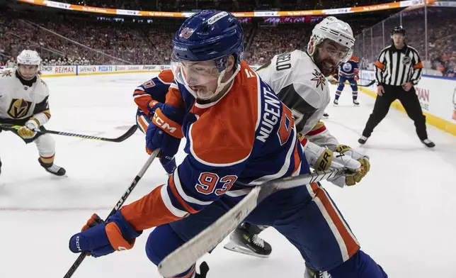 Vegas Golden Knights' Alex Pietrangelo, front right, and Edmonton Oilers' Ryan Nugent-Hopkins (93) battle for the puck during the second period of Game 4 of a second-round NHL hockey playoff series in Edmonton, Alberta, Monday, May 12, 2025. (Jason Franson/The Canadian Press via AP)