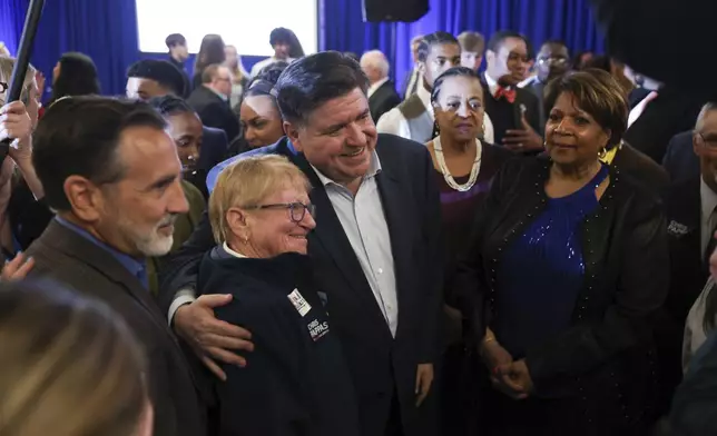 Illinois Gov. JB Pritzker, center, poses for a photo during the McIntyre-Shaheen 100 Club Dinner, Sunday April 27, 2025, in Manchester, N.H. (AP Photo/Reba Saldanha)