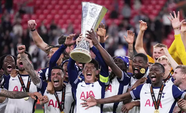 Tottenham's Son Heung-min holds the trophy aloft as he celebrates with teammates after winning the Europa League final soccer match against Manchester United at the San Mames Stadium in Bilbao, Spain, Wednesday, May 21, 2025. (AP Photo/Manu Fernandez)