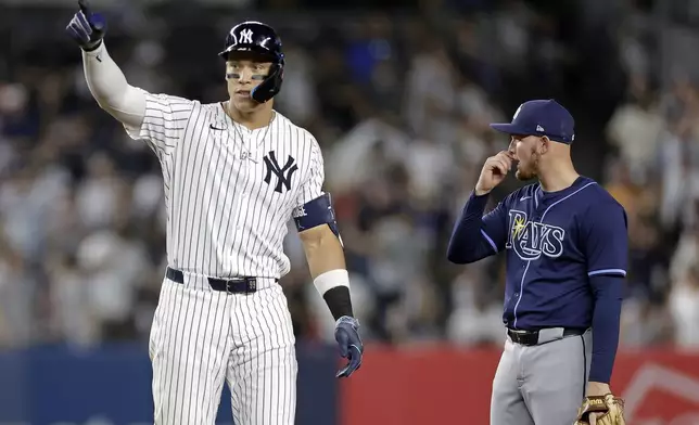 New York Yankees' Aaron Judge, left, reacts next to Tampa Bay Rays first baseman Curtis Mead after hitting a double during the fifth inning of a baseball game Friday, May 2, 2025, in New York. (AP Photo/Adam Hunger)