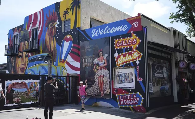 People take photographs next to a mural featuring a rooster on Calle Ocho in the Little Havana neighborhood of Miami, Wednesday, May 7, 2025. (AP Photo/Lynne Sladky)