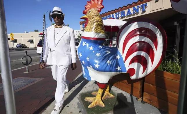 Alfredo Perez walks past a sculpture of a rooster on Calle Ocho in the Little Havana neighborhood of Miami, Wednesday, May 7, 2025. (AP Photo/Lynne Sladky)