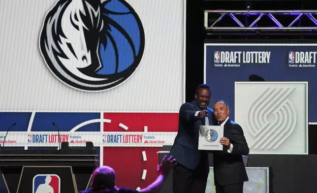 Dallas Mavericks' Rolando Blackman, left, and NBA Deputy Commissioner Mark Tatum, right, pose for photos after Tatum announced that the Mavericks had won the first pick in the NBA basketball draft lottery in Chicago, Monday, May 12, 2025. (AP Photo/Nam Y. Huh)