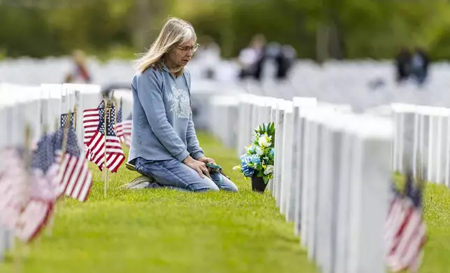 Stacey Buc visits the headstone of her mom, Felicia Buc, and dad, Tech. Chester Buc, after a Memorial Day ceremony on Sunday, May 25, 2025, at Great Lakes National Cemetery in Holly Township, Mich. (Ayrton Breckenridge/The Flint Journal via AP)