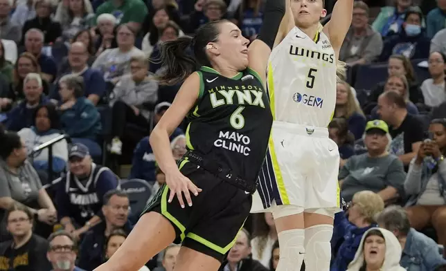 Dallas Wings guard Paige Bueckers (5) shoots over Minnesota Lynx forward Bridget Carleton (6) during the first half of a WNBA basketball game Wednesday, May 21, 2025, in Minneapolis. (AP Photo/Abbie Parr)