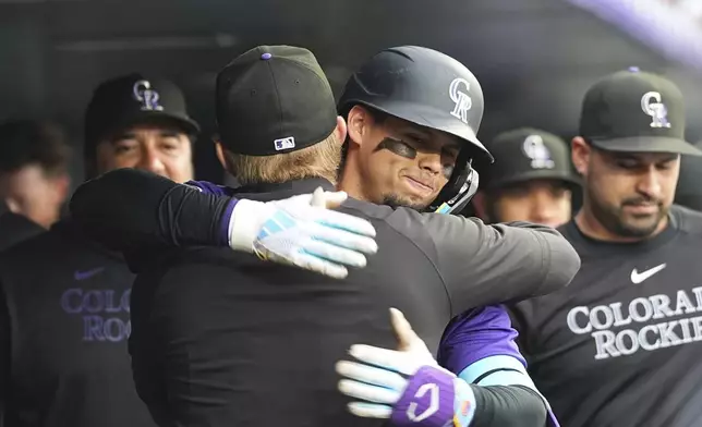 Colorado Rockies' Aaron Schunk, center left, congratulates Ezequiel Tovar, center right, who returns to the dugout after hitting a solo home run off Philadelphia Phillies starting pitcher Cristopher Sánchez in the first inning of a baseball game Monday, May 19, 2025, in Denver. (AP Photo/David Zalubowski)