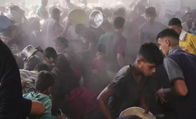 Palestinians struggle to get donated food at a community kitchen in Khan Younis, Gaza Strip, Friday, May 16, 2025. (AP Photo/Abdel Kareem Hana)