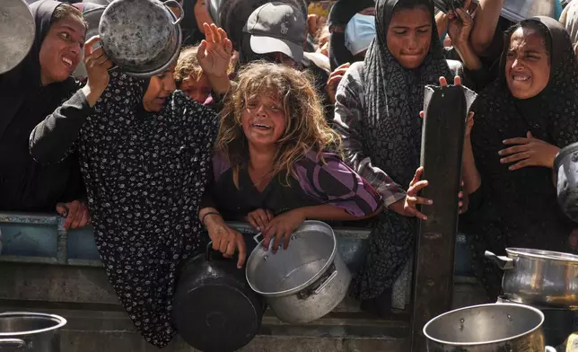Palestinians struggle to get donated food at a community kitchen in Khan Younis, Gaza Strip, Friday, May 16, 2025. (AP Photo/Abdel Kareem Hana)