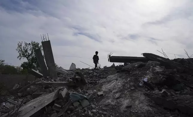 A Palestinian kid walks on the rubble of the Al-Zainati family's home, destroyed by Israeli airstrikes in Khan Younis, Gaza Strip, on Thursday, May 15, 2025. (AP Photo/Abdel Kareem Hana)