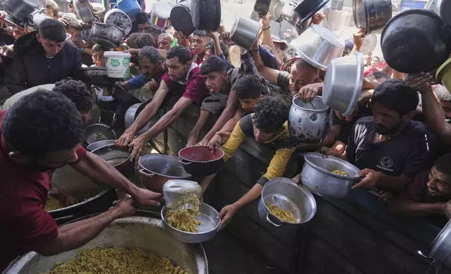 Palestinians struggle to get donated food at a community kitchen in Khan Younis, Gaza Strip, Friday, May 16, 2025. (AP Photo/Abdel Kareem Hana)