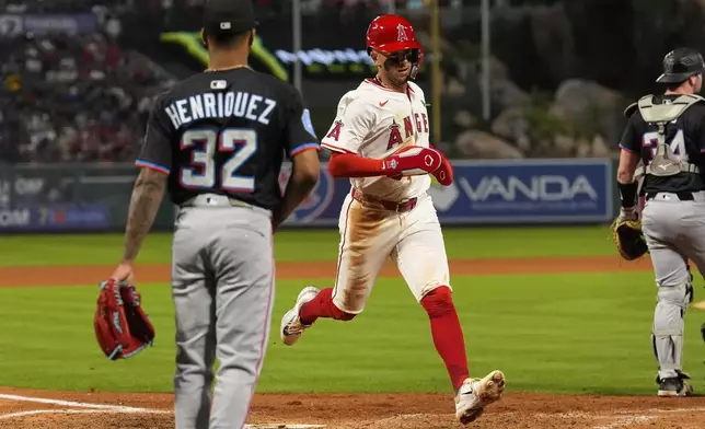 Los Angeles Angels' Zach Neto, center, scores on a sacrifice fly by Taylor Ward as Miami Marlins relief pitcher Ronny Henriquez,left, and catcher Liam Hicks stand by during the fourth inning of a baseball game Saturday, May 24, 2025, in Anaheim, Calif. (AP Photo/Mark J. Terrill)