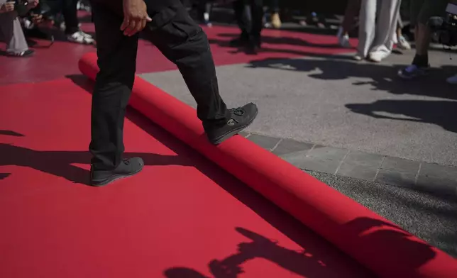 Crew members install the red carpet at the Palais des Festivals ahead of the opening ceremony of the 78th international film festival, Cannes, southern France, Tuesday, May 13, 2025. (AP Photo/Natacha Pisarenko)