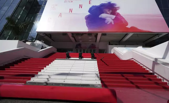 Crew members install the red carpet at the Palais des Festivals ahead of the opening ceremony of the 78th international film festival, Cannes, southern France, Tuesday, May 13, 2025. (AP Photo/Natacha Pisarenko)