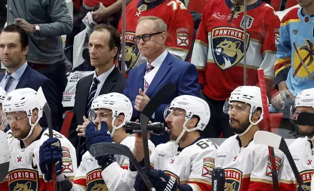 Florida Panthers head coach Paul Maurice, back center, waits for the results of his coaches challenge during the second period of Game 2 of the NHL hockey Stanley Cup Eastern Conference finals against the Carolina Hurricanes in Raleigh, N.C., Thursday, May 22, 2025. (AP Photo/Karl DeBlaker)