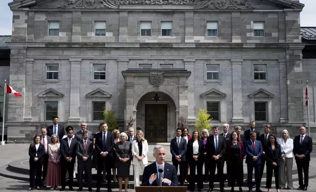 Members of Canada's Prime Minister Mark Carney's newly sworn in cabinet look on as Carney, center, speaks to reporters following a swearing-in ceremony at Rideau Hall in Ottawa, Ontario, Tuesday, May 13, 2025. (Spencer Colby/The Canadian Press via AP)