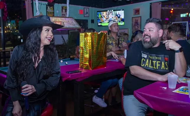 Audrey Campos, left, laughs with Jay Solis, 42, during a Loteria game night at Jackie O's Cocktail Club in Fort Worth, Texas, Tuesday, May 27, 2025. (AP Photo/Ronaldo Bolaños)