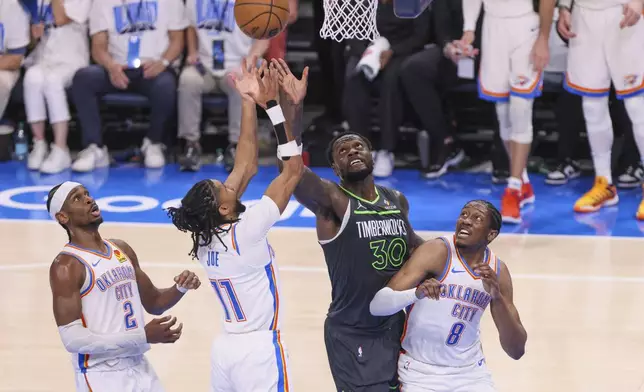 Minnesota Timberwolves forward Julius Randle (30) competes for a rebound against Oklahoma City Thunder guard Shai Gilgeous-Alexander (2), guard Isaiah Joe (11) and forward Jalen Williams (8) during the first half of Game 1 of an NBA basketball Western Conference Finals playoff series Tuesday, May 20, 2025, in Oklahoma City. (AP Photo/Nate Billings)