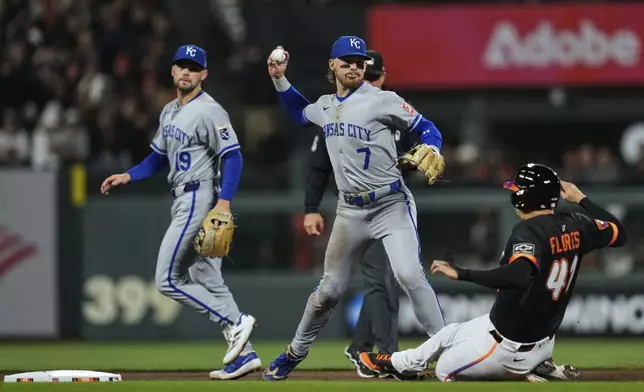 Kansas City Royals shortstop Bobby Witt Jr. (7) throws to first for a double play after forcing out San Francisco Giants' Wilmer Flores, right, at second during the seventh inning of a baseball game Tuesday, May 20, 2025, in San Francisco. Heliot Ramos was out at first on the play. (AP Photo/Godofredo A. Vásquez)