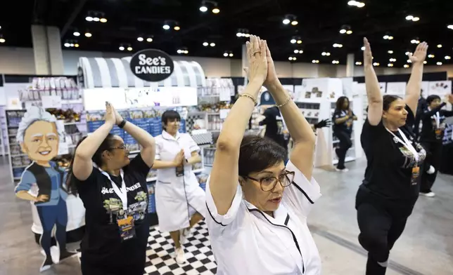 Marcy Gomez of Pasadena, Cal., does yoga with fellow See's Candies employees before doors open to shareholders at CHI Health Center Omaha for the Berkshire Hathaway annual meeting Saturday, May 3, 2025, in Omaha, Neb. (AP Photo/Rebecca S. Gratz)