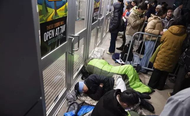 From front, shareholders Haibo Liu, Liyang Jiang and Cheng Guo of China rest in sleeping bags outside CHI Health Center Omaha for the Berkshire Hathaway annual meeting Saturday, May 3, 2025, in Omaha, Neb. The group arrived at 11 p.m. the night before to retain a spot at the front of the line. (AP Photo/Rebecca S. Gratz)