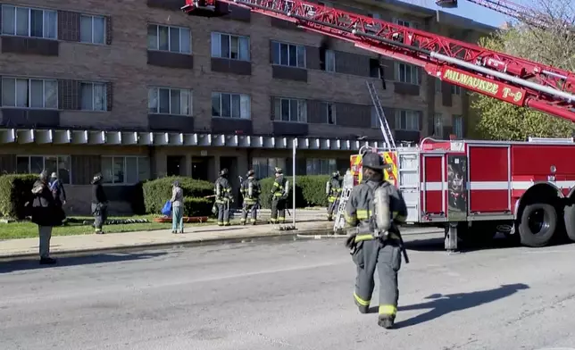 This image taken from video provided by WISN shows firefighters working at the site of an apartment building fire in Milwaukee, Wis., Sunday, May 11, 2025. (WISN via AP)