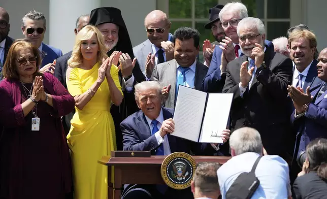 President Donald Trump, surrounded by religious leaders, holds up a signed executive order during a National Day of Prayer event in the Rose Garden of the White House, Thursday, May 1, 2025, in Washington. (AP Photo/Alex Brandon)