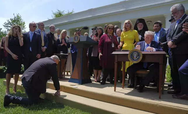 President Donald Trump, surrounded by religious leaders, signs an executive order establishing the Religious Liberty Commission, during a National Day of Prayer event in the Rose Garden of the White House, Thursday, May 1, 2025, in Washington. (AP Photo/Evan Vucci)