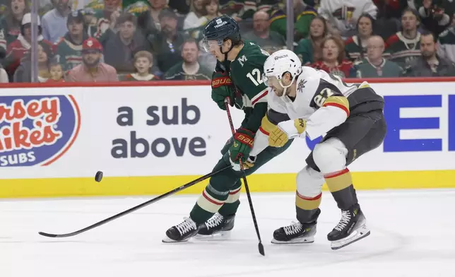 Minnesota Wild left wing Matt Boldy (12) and Vegas Golden Knights defenseman Shea Theodore (27) battle for the puck during the first period of Game 6 of a first-round NHL hockey playoff series Thursday, May 1, 2025, in St. Paul, Minn. (AP Photo/Bailey Hillesheim)