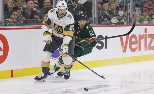 Minnesota Wild left wing Matt Boldy (12) and Vegas Golden Knights defenseman Shea Theodore (27) battle for the puck during the first period of Game 6 of a first-round NHL hockey playoff series Thursday, May 1, 2025, in St. Paul, Minn. (AP Photo/Bailey Hillesheim)
