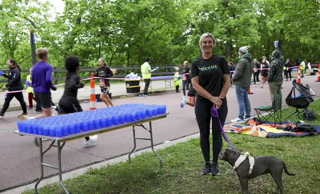 Kristina Smithe, founder of Hiccup, a reusable silicone cup, stands for a portrait with her rescue dog, Tina, during the PNC Women Run the Cities race on Saturday, May 17, 2025, in Minneapolis. (AP Photo/Ellen Schmidt)