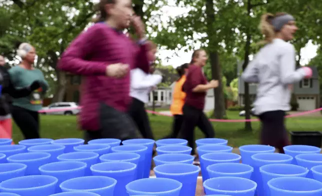 Runners pass a table with reusable silicone cups from Hiccup during the PNC Women Run the Cities race on Saturday, May 17, 2025, in Minneapolis. (AP Photo/Ellen Schmidt)