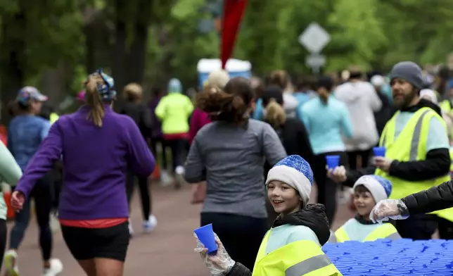 Eddie Ashton, 10, of St. Paul, Minn., hands out a reusable silicone cup by Hiccup along the PNC Women Run the Cities route on Saturday, May 17, 2025, in Minneapolis. (AP Photo/Ellen Schmidt)