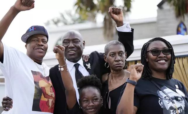 Attorney Ben Crump, second from left, raises his fist with George Floyd's sisters, LeTonya Floyd, left, and Zsa Zsa Floyd, second from left, along with great niece Arianna Williams, 7, and niece Bianca Williams, right, before a memorial service on the anniversary of Floyd's death on Sunday, May 25, 2025, in Houston. (AP Photo/Ashley Landis)