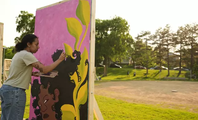 Eva Ngono works on a painting in a park near George Floyd Square on the five-year anniversary of Floyd's death, Sunday, May 25, 2025, in Minneapolis. (AP Photo/Abbie Parr)