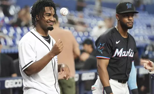 Miami Dolphins wide receiver Jaylen Waddle, left, tosses a baseball as he stands with Miami Marlins' Otto Lopez, right, before throwing a ceremonial pitch before a baseball game against the San Francisco Giants, Friday, May 30, 2025, in Miami. (AP Photo/Lynne Sladky)
