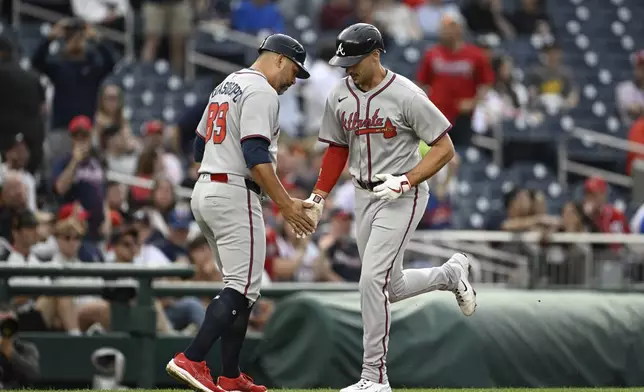 Atlanta Braves' Matt Olson is greeted by third base coach Matt Tuiasosopo (89) after hitting a solo home run against Washington Nationals pitcher Mitchell Parker during the second inning of a baseball game in Washington, Tuesday, May 20, 2025. (AP Photo/Terrance Williams)