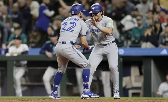 Toronto Blue Jays' Ernie Clement (22) celebrates with Addison Barger, right, after scoring against the Seattle Mariners during the eighth inning of a baseball game, Saturday, May 10, 2025, in Seattle. (AP Photo/John Froschauer)