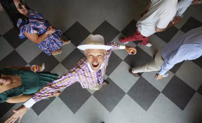 A race fan smiles at Churchill Downs before the 151st running of the Kentucky Oaks horse race Friday, May 2, 2025, in Louisville, Ky. (AP Photo/Charlie Riedel)