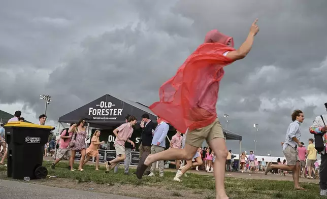 A fan runs as weather blows in at Churchill Downs before the 151st running of the Kentucky Oaks horse race Friday, May 2, 2025, in Louisville, Ky. (AP Photo/Jon Cherry)