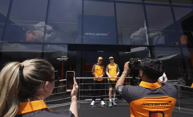 McLaren driver Lando Norris of Britain, left, is flaked by his teammate Oscar Piastri of Australia in the paddock at the Dino and Enzo Ferrari racetrack, ahead the Italy's Emilia Romagna Formula One Grand Prix in Imola, Italy, Thursday, May 15, 2025. (AP Photo/Antonio Calanni)