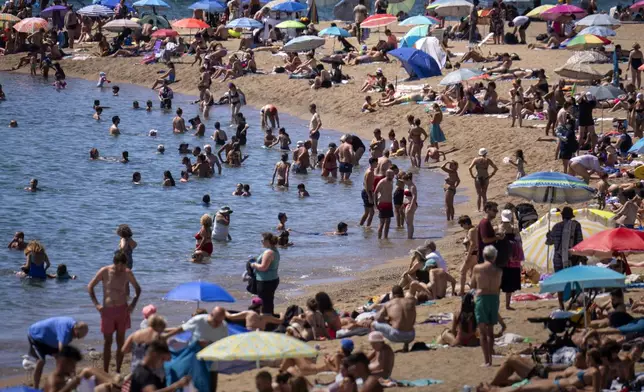 FILE - Bathers cool off in the water while others sunbathe on a Barcelona beach, Spain, Wednesday, July 24, 2024. (AP Photo/Emilio Morenatti,File)
