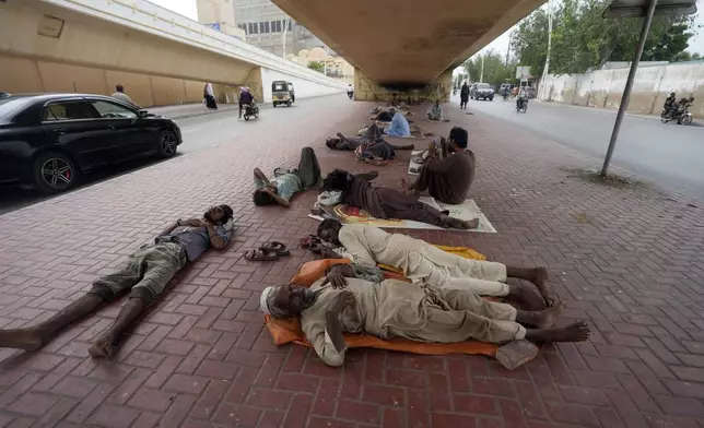 FILE - Laborers sleep under a bridge during a hot summer day in Karachi, Pakistan, Thursday, July 25, 2024. (AP Photo/Fareed Khan,File)