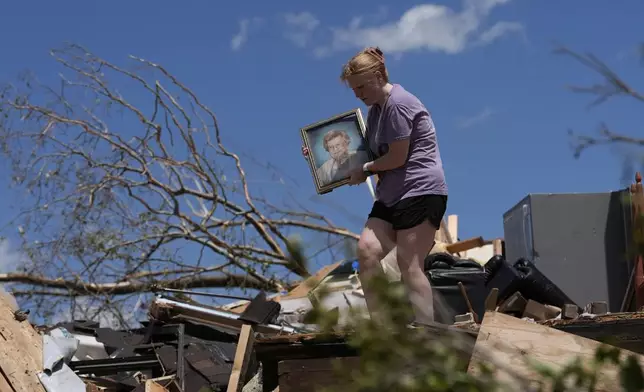 Hailee Allen holds a family picture saved from Lynn and Don White's home, Saturday, May 17, 2025, in London, Ky (AP Photo/Carolyn Kaster)